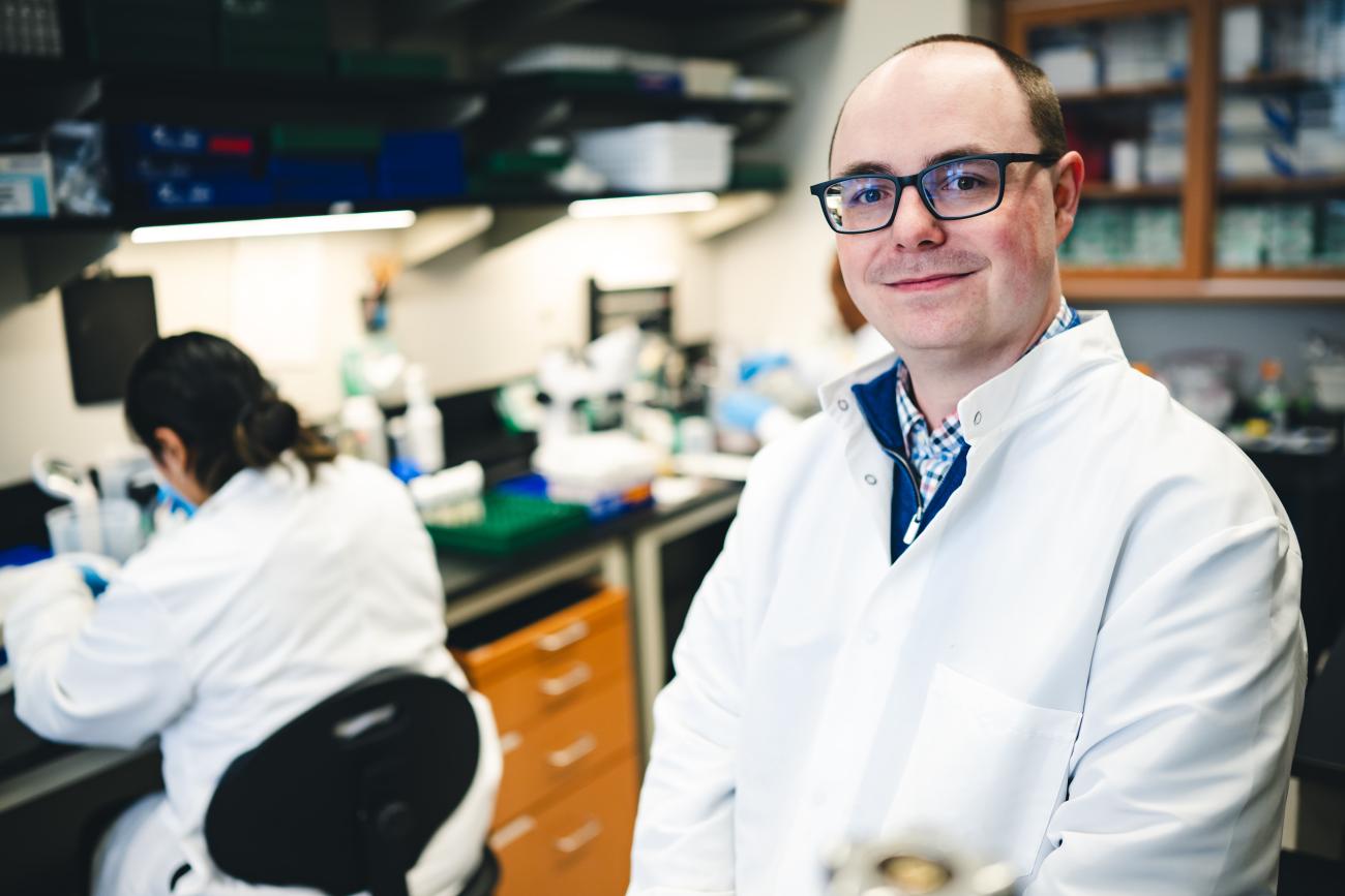 Dylan Shropshire, assistant professor of biological sciences in a lab smiling.